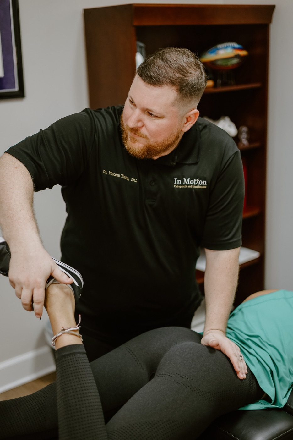 Dr. Torina guiding a patient through an assisted stretch during a sports rehab session